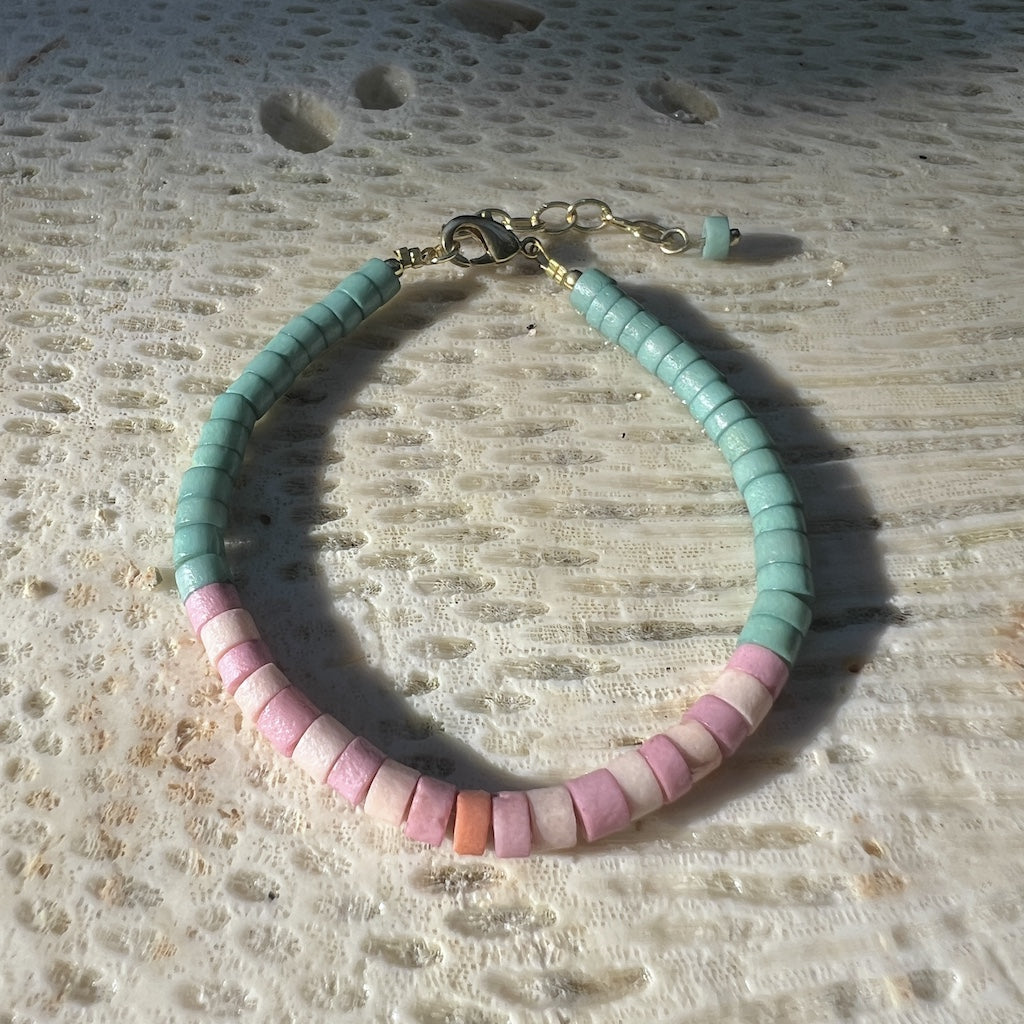 Bracelet with green and pink beads on a white background